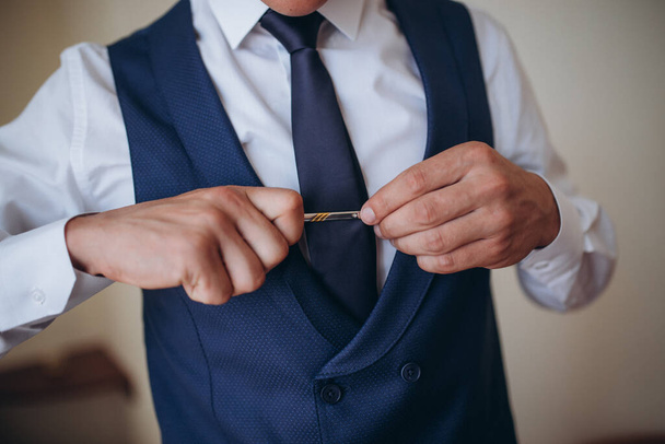 Grooms morning preparation, handsome groom getting dressed and preparing for the wedding, in dark blue suit - Photo, Image