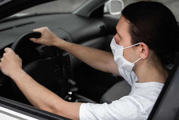 Man in protective medical mask for protect himself from bacteria and virus is planning to drive a car. Protective mask while epidemic, quarantine, world pandemic, covid 19, coronavirus, infection. - Foto, Imagem