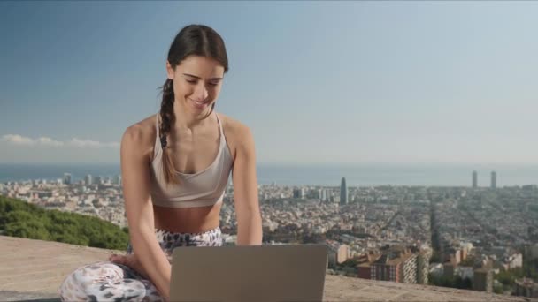 Frau in Lotus-Pose mit Laptop im Freien. Mädchen tippt in der Stadt auf Laptop - Filmmaterial, Video