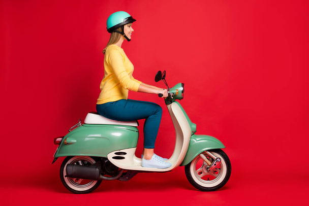 Profile side view portrait of her she nice attractive lovely confident cheerful cheery girl riding moped spending weekend isolated on bright vivid shine vibrant red color background - Foto, immagini