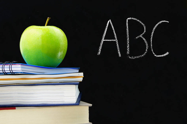 ABC kirjoitettu liitutaulu koulun kirjoja ja omena edessä
 - Valokuva, kuva
