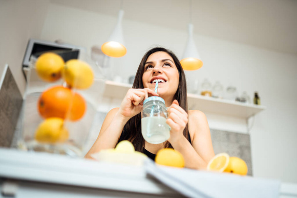 Healthy cheerful woman drinking homemade organic mixed citrus fruit drink.Making lemonade.Detox diet,nutrition.Food for oily skin,strong immune system,fitness meal.Natural antioxidants vitamins source - Fotó, kép