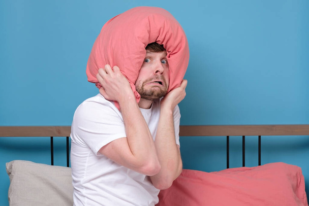 Cauacsian young man with pillow on head in bed being afraid being alone stressed because of quarantine - Photo, Image