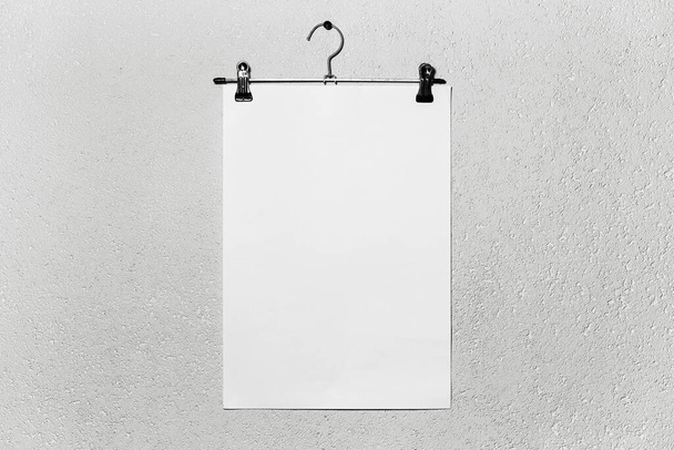 Mockup του λευκού χαρτιού που συνδέονται με κρεμάστρα ύφασμα σε λευκό υφή φόντο. - Φωτογραφία, εικόνα