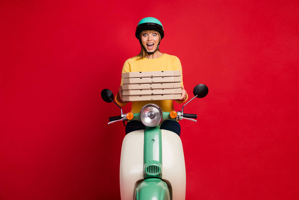 Portrait of her she nice attractive amazed cheerful cheery girl sitting on moped holding in hands pile stack dessert sale discount isolated on bright vivid shine vibrant red color background - Foto, immagini