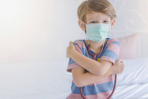 Маленький мальчик носить маску и обнимает себя знак для защиты вируса "Любите себя просто остаться дома
" - Фото, изображение