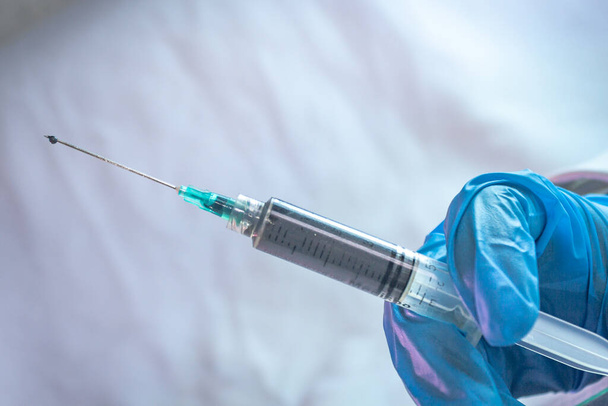 Impfstoff in Spritze zur Behandlung von Covid 19 mit blauen Handschuhen - Foto, Bild