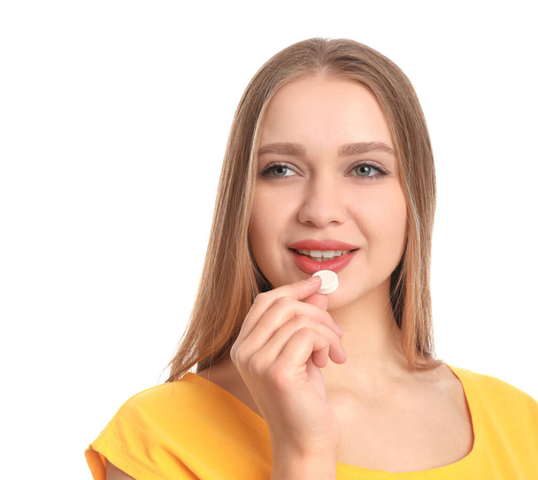 Young woman taking vitamin pill on white background - Fotoğraf, Görsel