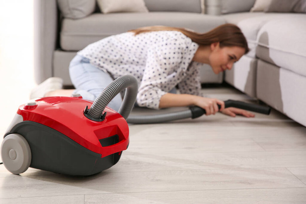 Young woman using vacuum cleaner at home - Photo, Image