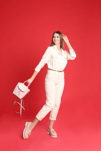 Beautiful young woman in casual outfit with stylish bag on red background - Foto, Bild