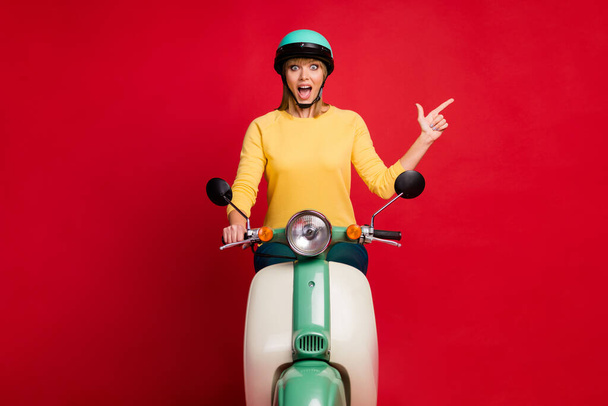 Portrait of her she nice attractive cheerful cheery amazed astonished girl riding moped showing copy space like follow subscribe isolated on bright vivid shine vibrant red color background - Foto, Bild
