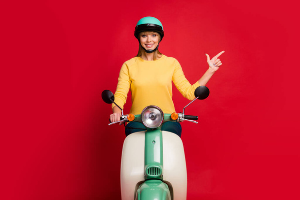 Portrait of her she nice attractive lovely cheerful cheery confident girl riding moped showing copy empty blank space isolated on bright vivid shine vibrant red color background - Photo, Image