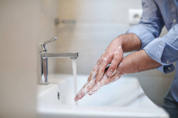 Coronavirus infection and spreading prevention, proper Washing hands with liquid soap. Hygiene male antibacterial hands water wash closeup in bathroom. - Photo, Image
