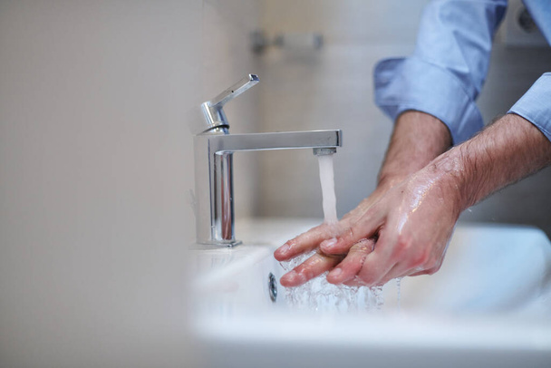 Coronavirus infection and spreading prevention, proper Washing hands with liquid soap. Hygiene male antibacterial hands water wash closeup in bathroom. - Photo, image