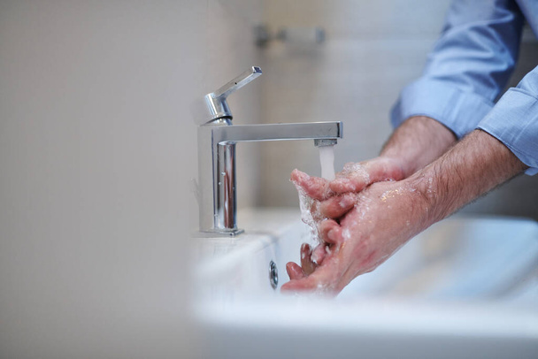 Coronavirus infection and spreading prevention, proper Washing hands with liquid soap. Hygiene male antibacterial hands water wash closeup in bathroom. - Foto, Bild