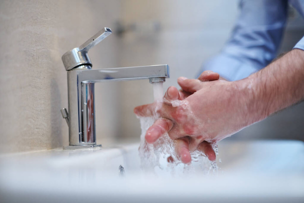 Coronavirus infection and spreading prevention, proper Washing hands with liquid soap. Hygiene male antibacterial hands water wash closeup in bathroom. - Foto, immagini