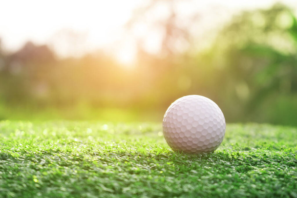 Golfbälle auf grünen Rasenflächen auf wunderschönen Golfplätzen mit Sonnenaufgangshintergrund.Wichtige Ausrüstung zum Golfspiel.Sportarten, die Menschen auf der ganzen Welt in den Ferien für die Gesundheit ausüben. - Foto, Bild