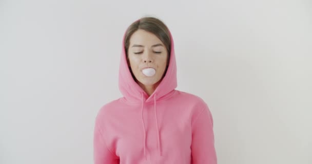 girl dressed in pink hoodie blowing bubblegum - 映像、動画