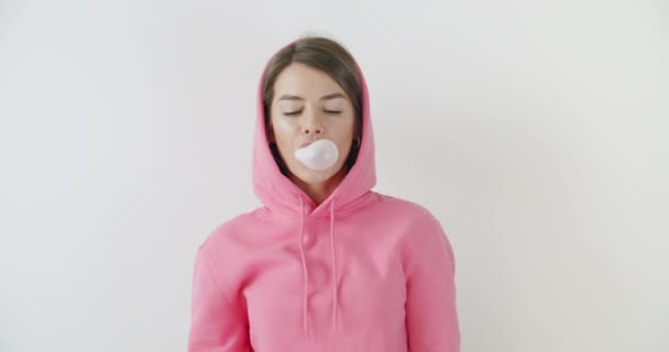 girl dressed in pink hoodie blowing bubblegum - Πλάνα, βίντεο