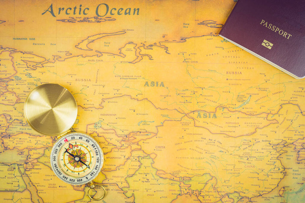 Concept d'accessoires de voyage : Il est temps d'aller voyager autour du monde - L'image d'une carte du monde avec des accessoires essentiels - passeport et boussole. Style de ton vintage. Image de vue supérieure
. - Photo, image