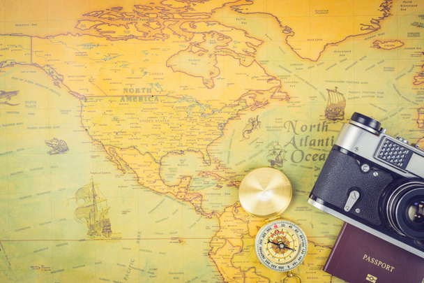 Concept d'accessoires de voyage : Il est temps de voyager autour du monde - L'image d'une carte du monde avec des accessoires essentiels - passeport, boussole et appareil photo. Style de ton vintage. Image de vue supérieure
. - Photo, image