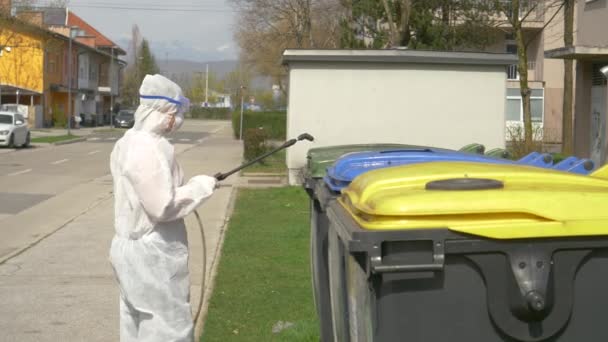 CERRAR: Persona en traje de materiales peligrosos rocía contenedores de basura con productos químicos antivirales. - Imágenes, Vídeo
