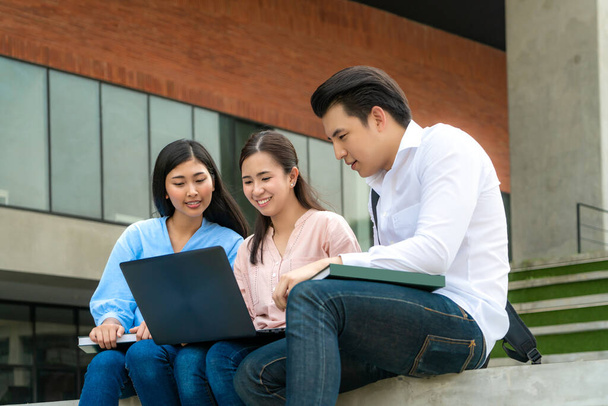 3人のアジアの学生は、大学のラップトップでの試験準備、プレゼンテーション、研究、試験準備のための研究について議論しています。教育、学習、学生、キャンパス、大学、ライフスタイルの概念. - 写真・画像