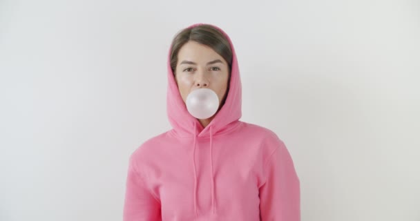 girl dressed in pink hoodie blowing bubblegum - Πλάνα, βίντεο