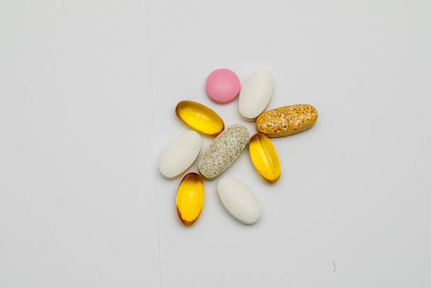 Capsules and tablets of different colors and shapes on a white background. Vitamins, Sports nutrition. Top view, close-up, selective focus. - Foto, Imagem