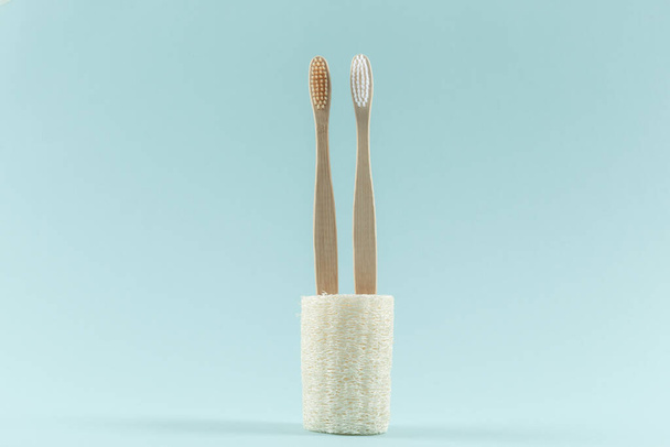 Two environmentally friendly toothbrushes are in the environmental loofah. Zero waste. On a blue background. - Fotoğraf, Görsel