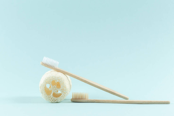 Two toothbrushes made of wood. Natural loofah product for the body. Zero Waste. On a trendy blue background. - Fotoğraf, Görsel