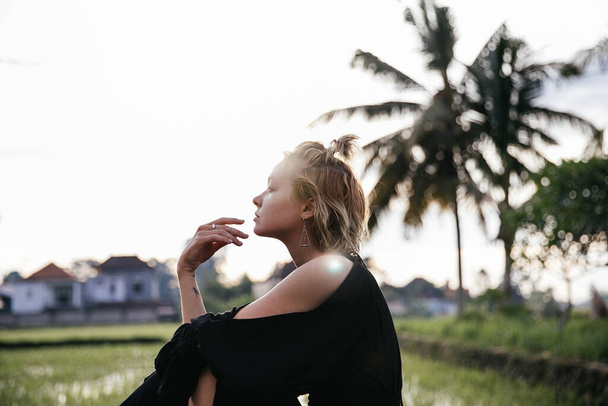 blonde blogger girl doing yoga and meditation in a rice field while traveling in Indonesia to Bali - Foto, afbeelding