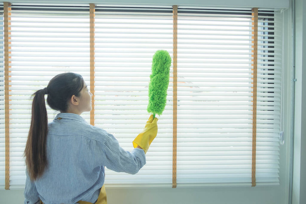 Temizlik ekibi pencere yüzeyinde panjurlu bir bez ve toz fırçası kullanıyor ve mikropları ve virüsleri öldürmek için temizlik maddesi kullanıyor.. - Fotoğraf, Görsel