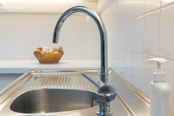Раковина из нержавеющей стали на кухне с белой плиткой на стене
 - Фото, изображение