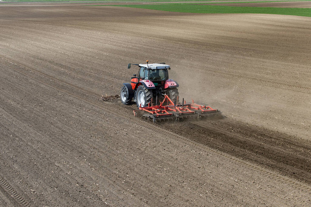 Tractor werkzaam in het veld, voorbereiding van de grond voor aanplant, werkend geploegd veld - Foto, afbeelding