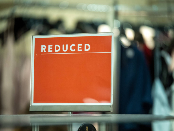 Cartel de venta de precio reducido naranja en estante de ropa en grandes almacenes
 - Foto, imagen