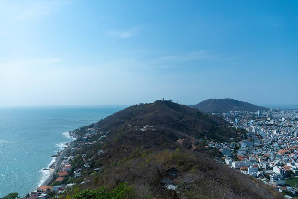 An aerial shot of a mountain coast bordering the city of Vung Tau in Vietnam under a blue sky - Foto, Imagen