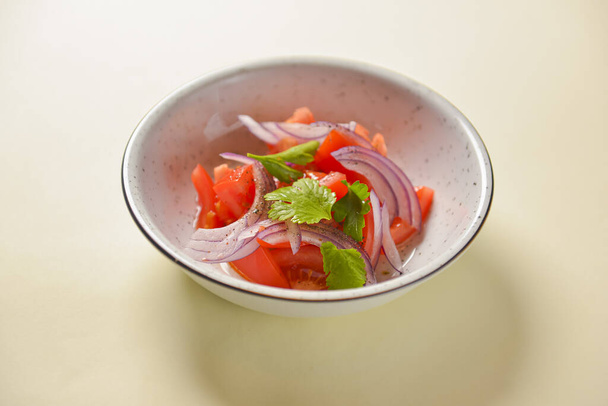 Fresh salad with red onion, tomatoes and basil. Served in a white bowl over bright background. - Zdjęcie, obraz