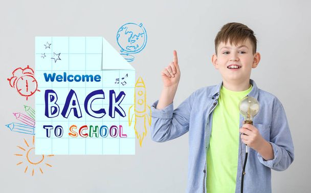 Little boy with light bulb and text WELCOME BACK TO SCHOOL on grey background - Photo, Image