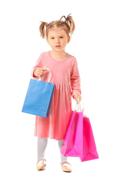 Beyaz arka planda alışveriş torbaları olan sevimli küçük bir kız. - Fotoğraf, Görsel