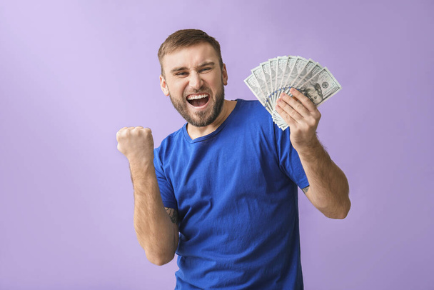 Happy young man with money on color background - Fotoğraf, Görsel