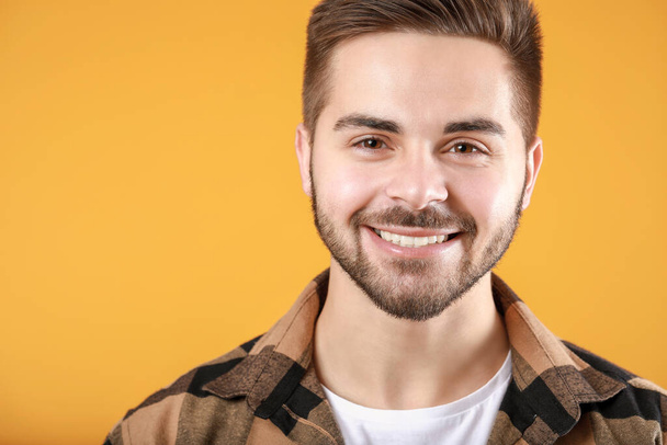 Schöner lächelnder junger Mann auf farbigem Hintergrund - Foto, Bild