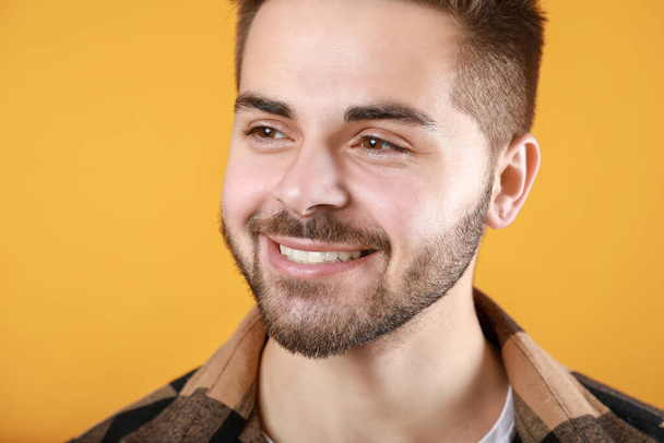 Schöner lächelnder junger Mann auf farbigem Hintergrund - Foto, Bild