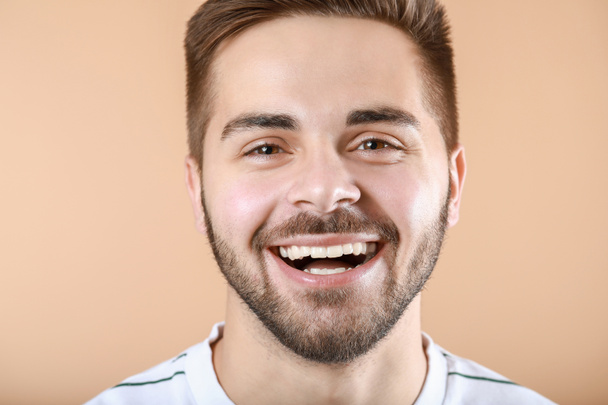 Jóképű mosolygós fiatalember a színes háttér - Fotó, kép