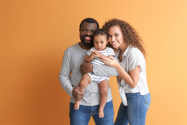Glückliche afroamerikanische Eltern mit niedlichem Baby auf farbigem Hintergrund - Foto, Bild