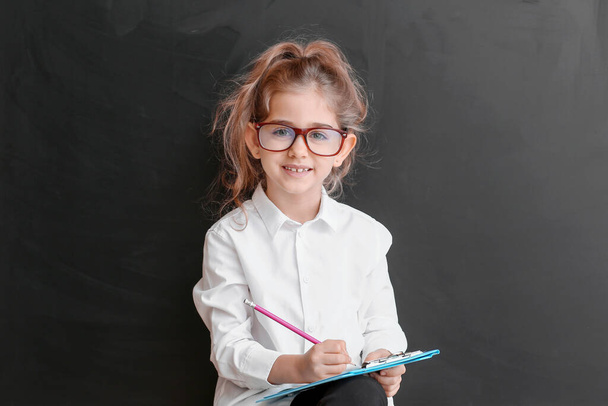 Aranyos kis iskoláslány a táblánál az osztályteremben. - Fotó, kép