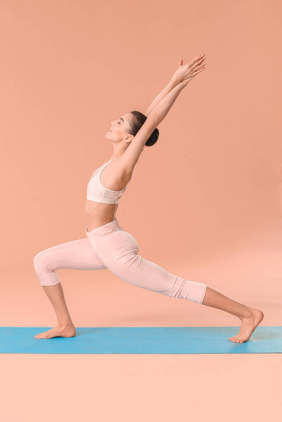 Junge Frau praktiziert Yoga auf farbigem Hintergrund - Foto, Bild