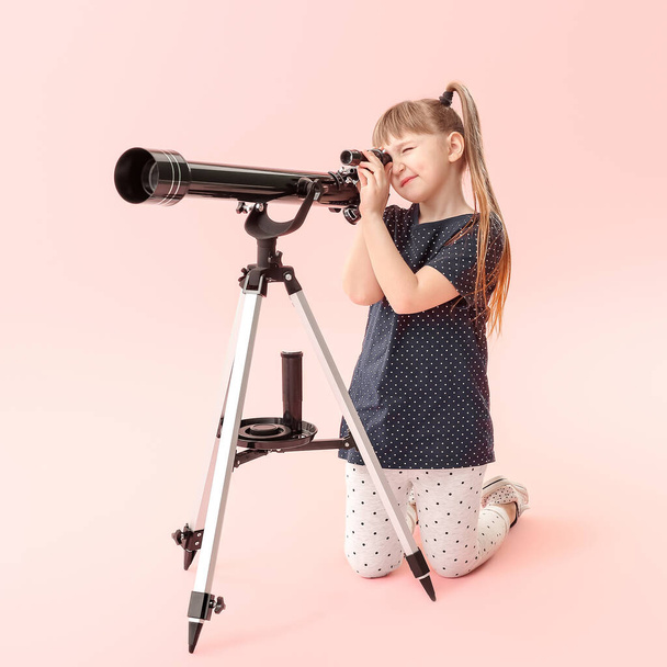 Cute little girl with telescope on color background - 写真・画像