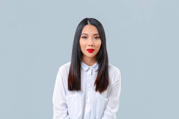 Jovem mulher asiática com cabelo bonito no fundo cinza
 - Foto, Imagem