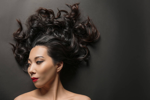Joven mujer asiática con hermoso cabello sobre fondo oscuro
 - Foto, Imagen